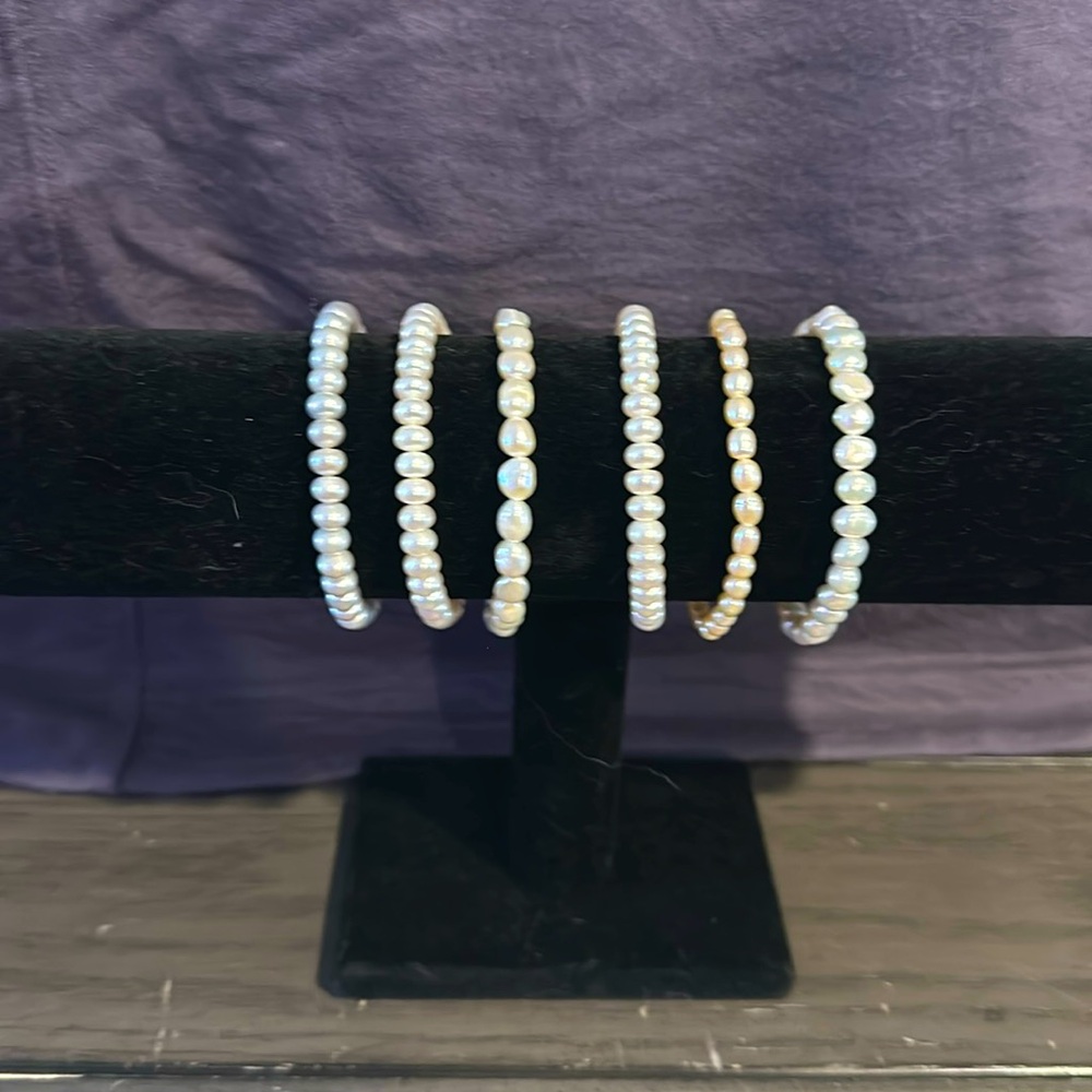 Set of six bead bracelets . Four are white , one light pink , one light grey